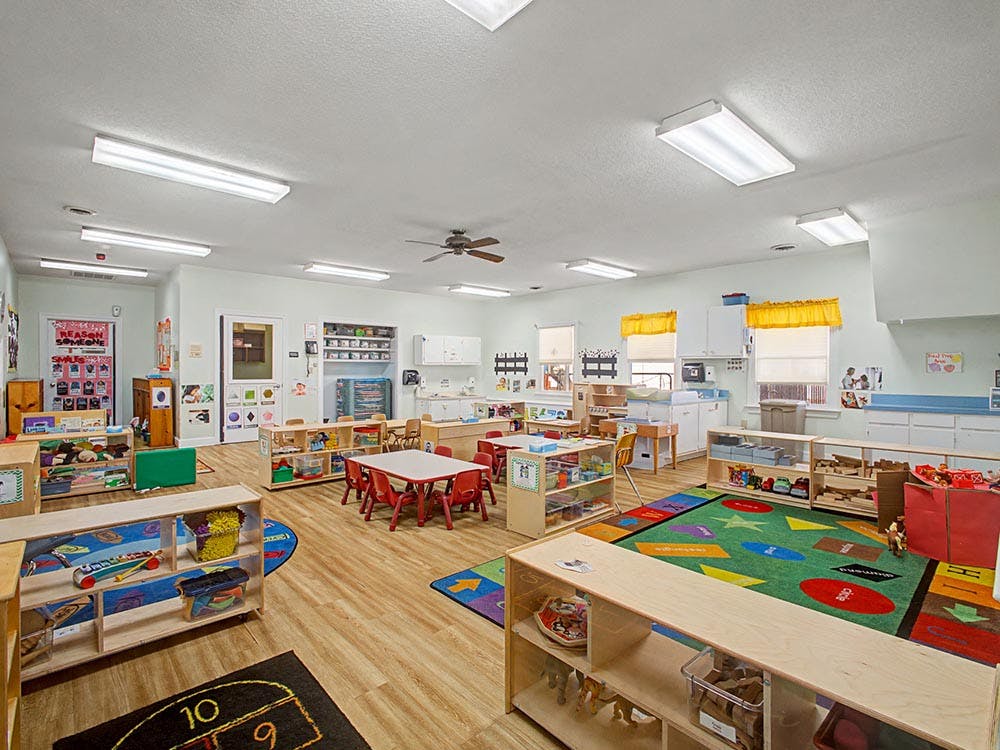 Classroom with small tables, chairs, and play areas