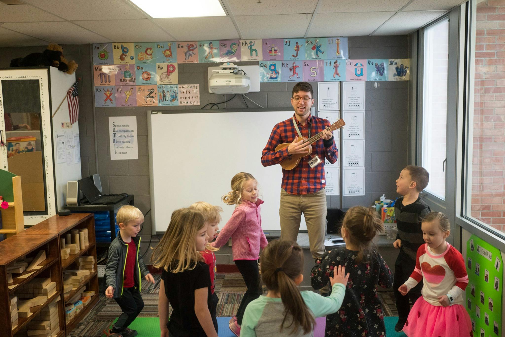 Person playing ukulele for children in a classroom