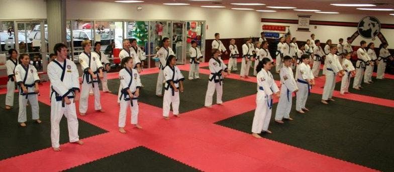 Group of people and children in martial arts uniforms standing in a studio