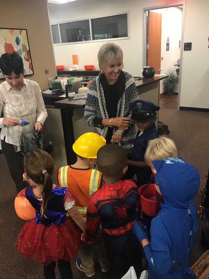 Two adults interacting with children in costumes