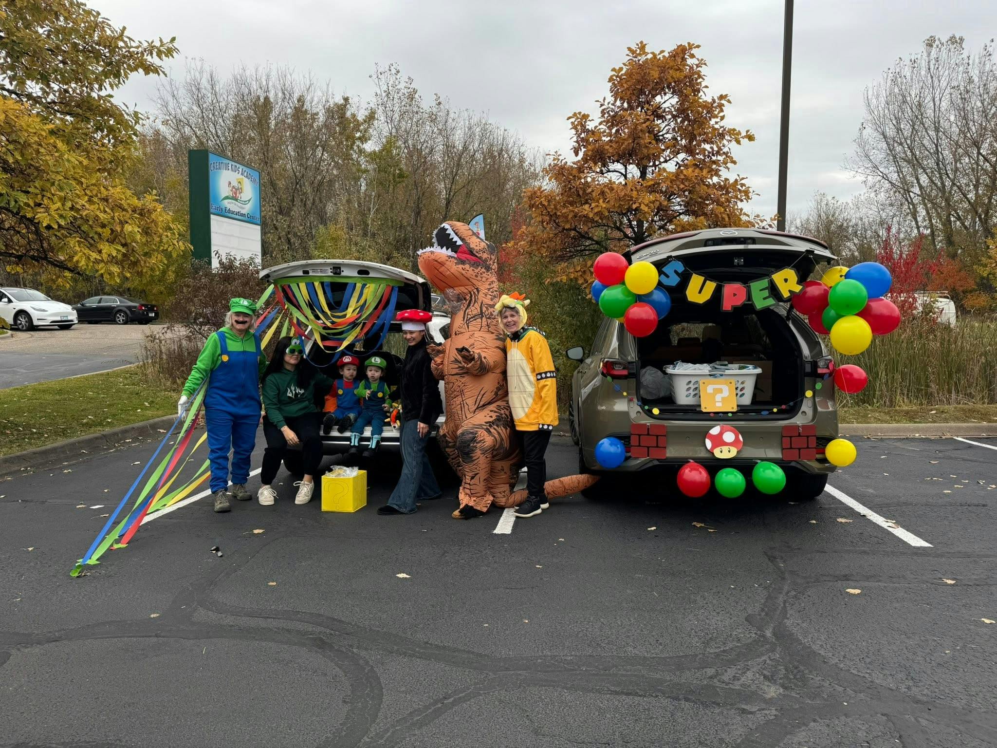 People in costumes standing by vehicles decorated for a trunk-or-treat event