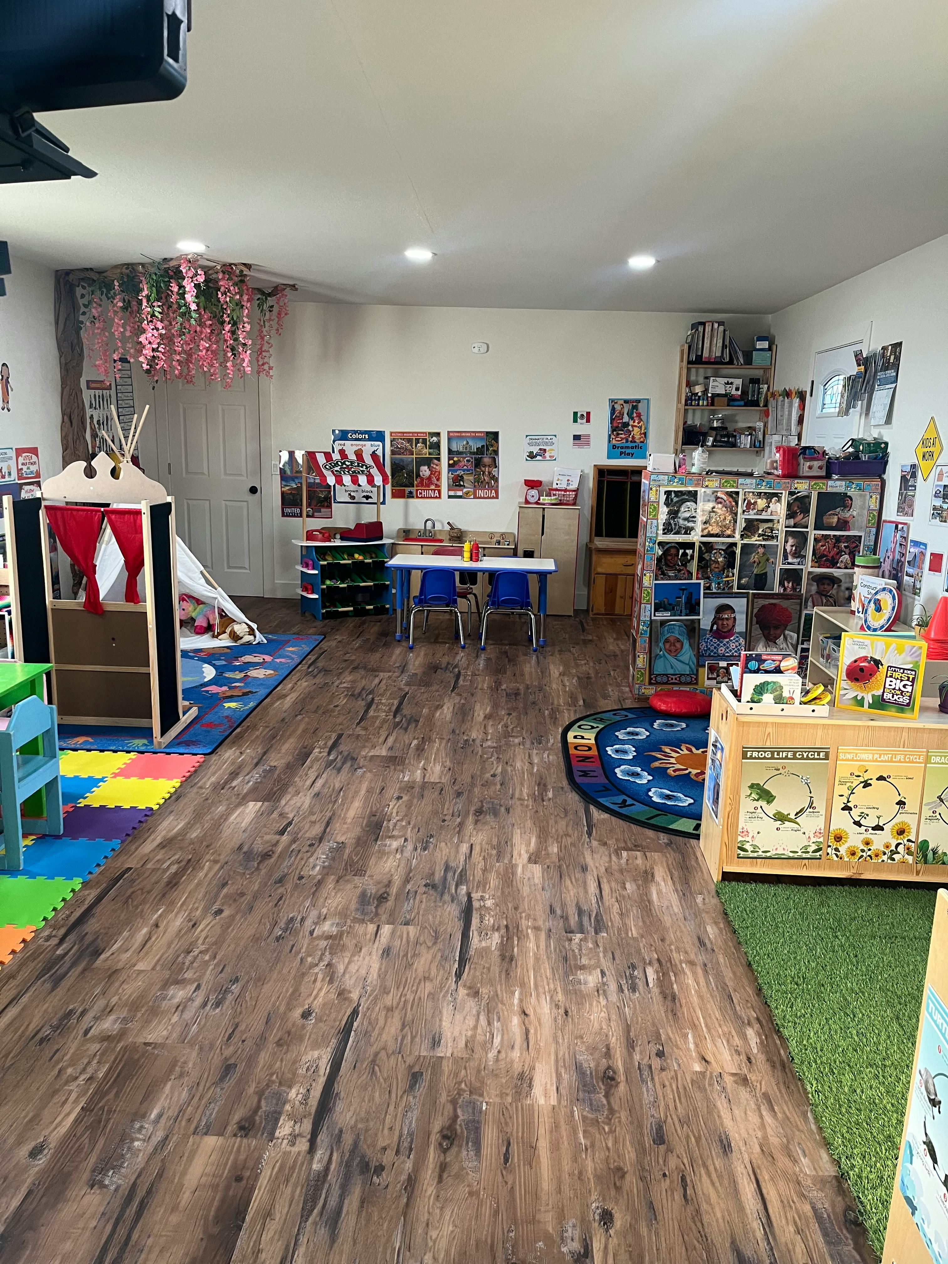 A classroom with play areas, tables, and shelves of books