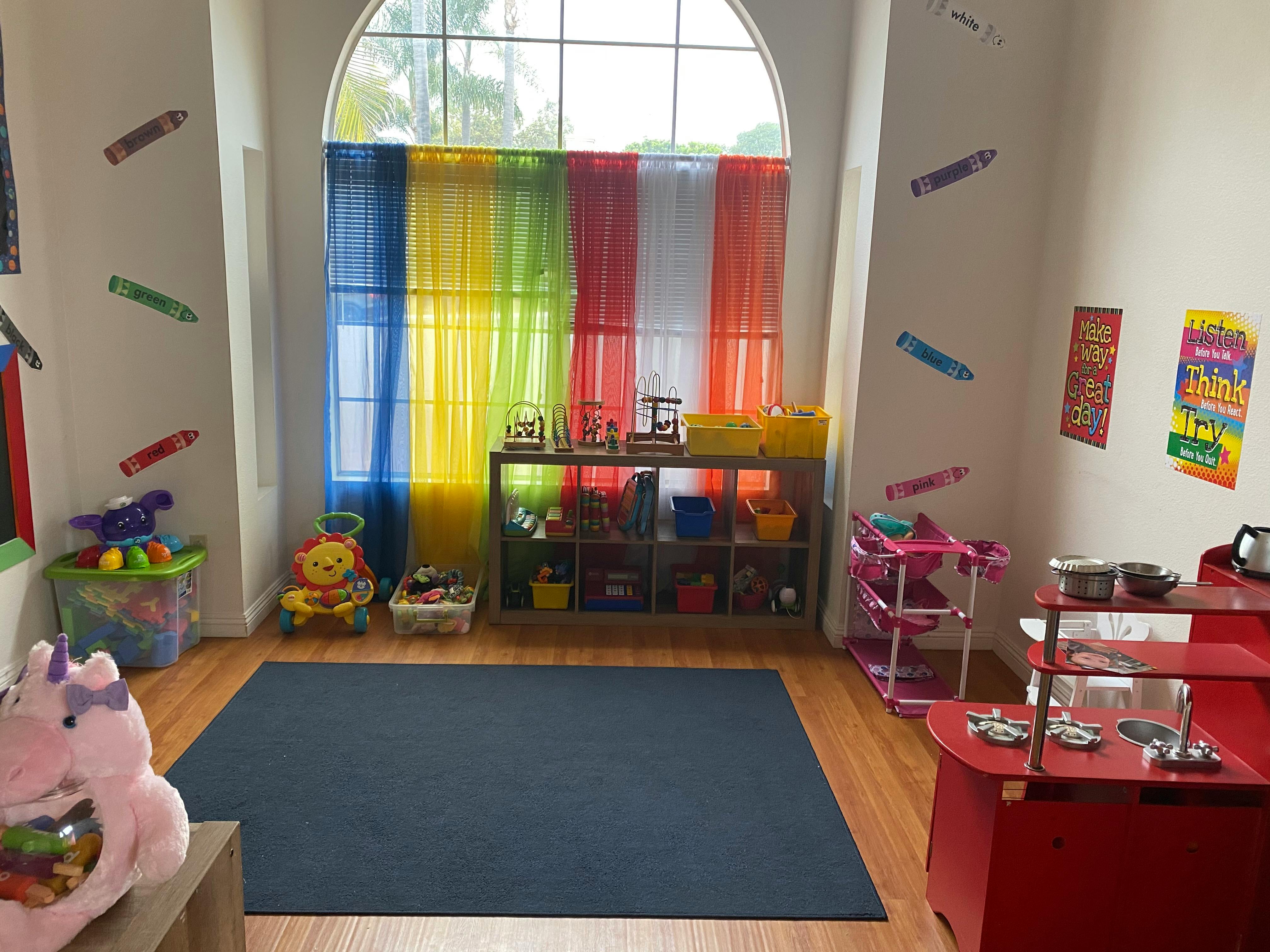 Playroom with colorful curtains, toys, and a blue rug