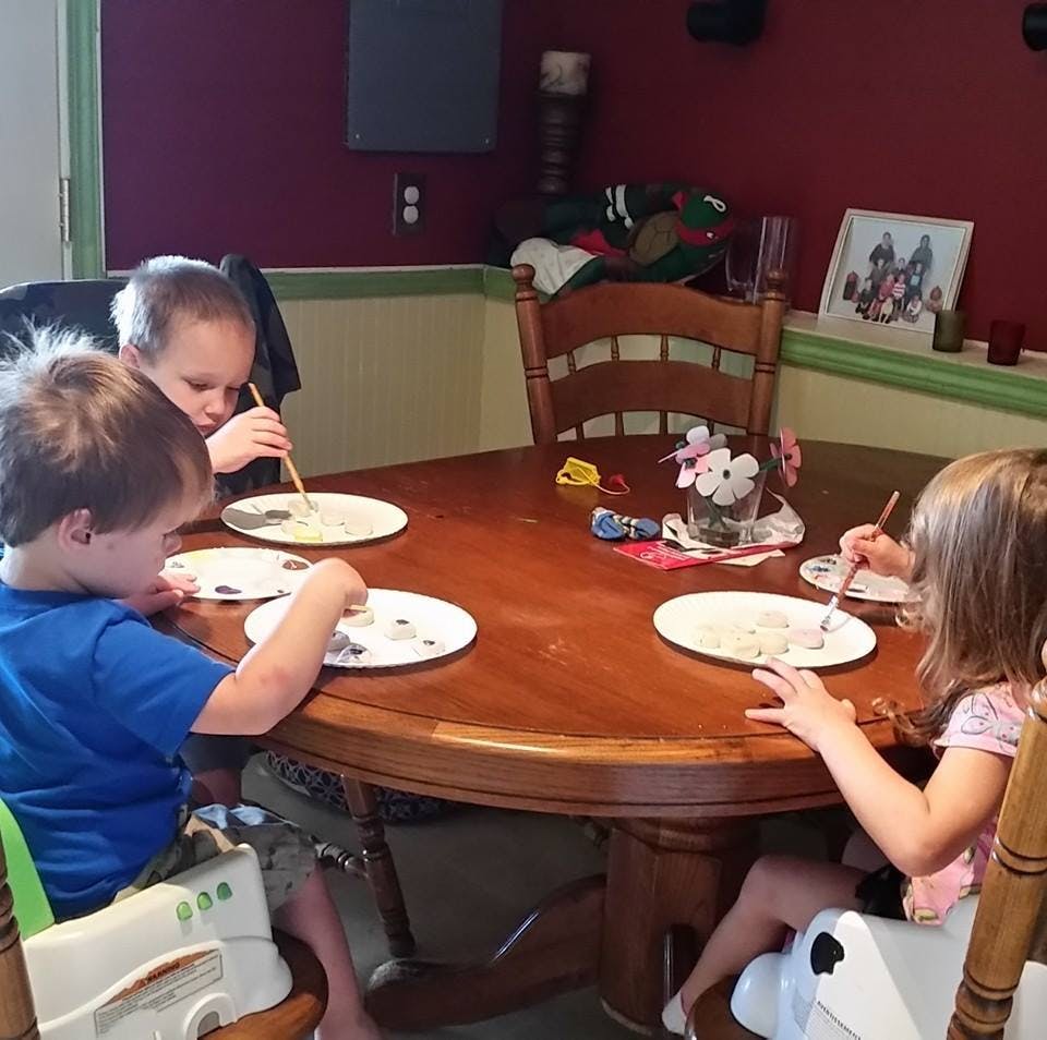 Three children eating at a round wooden table