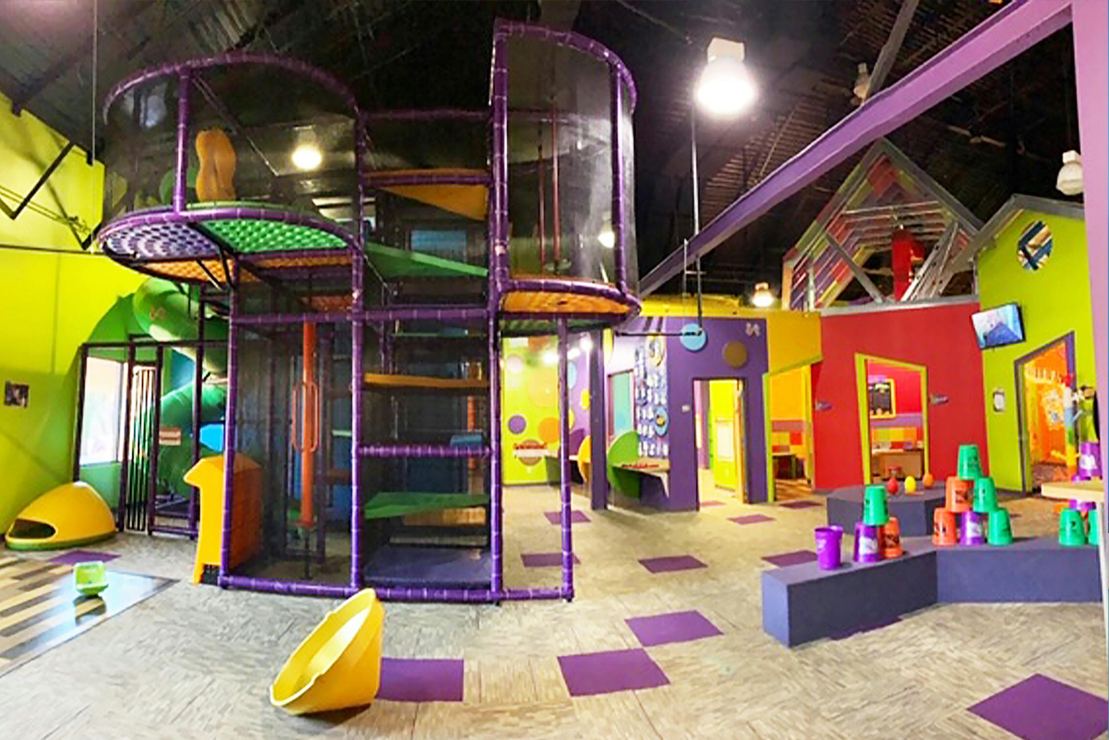 Indoor playground with a large purple play structure and colorful walls