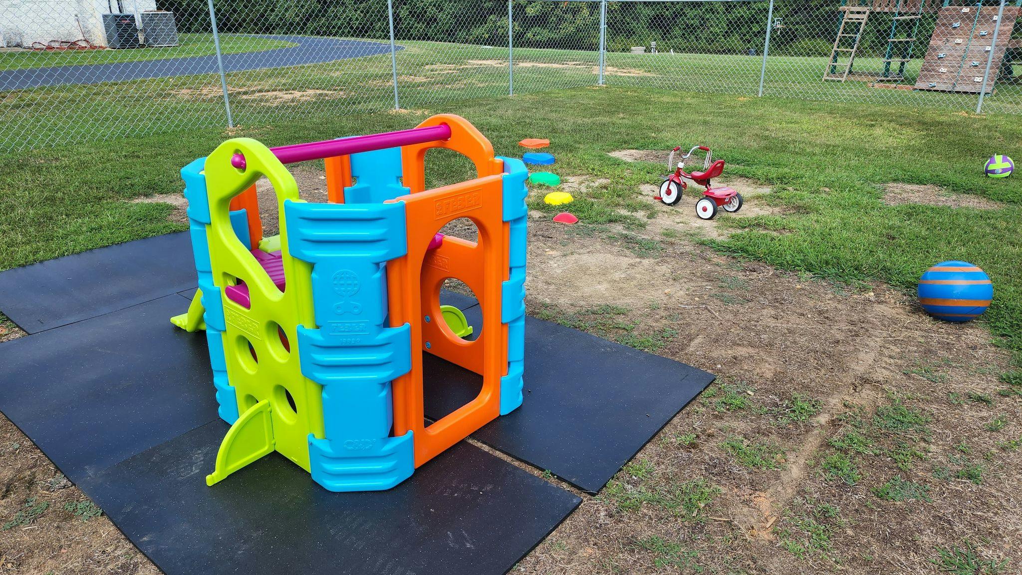 Colorful play structure on black mats in a grassy area