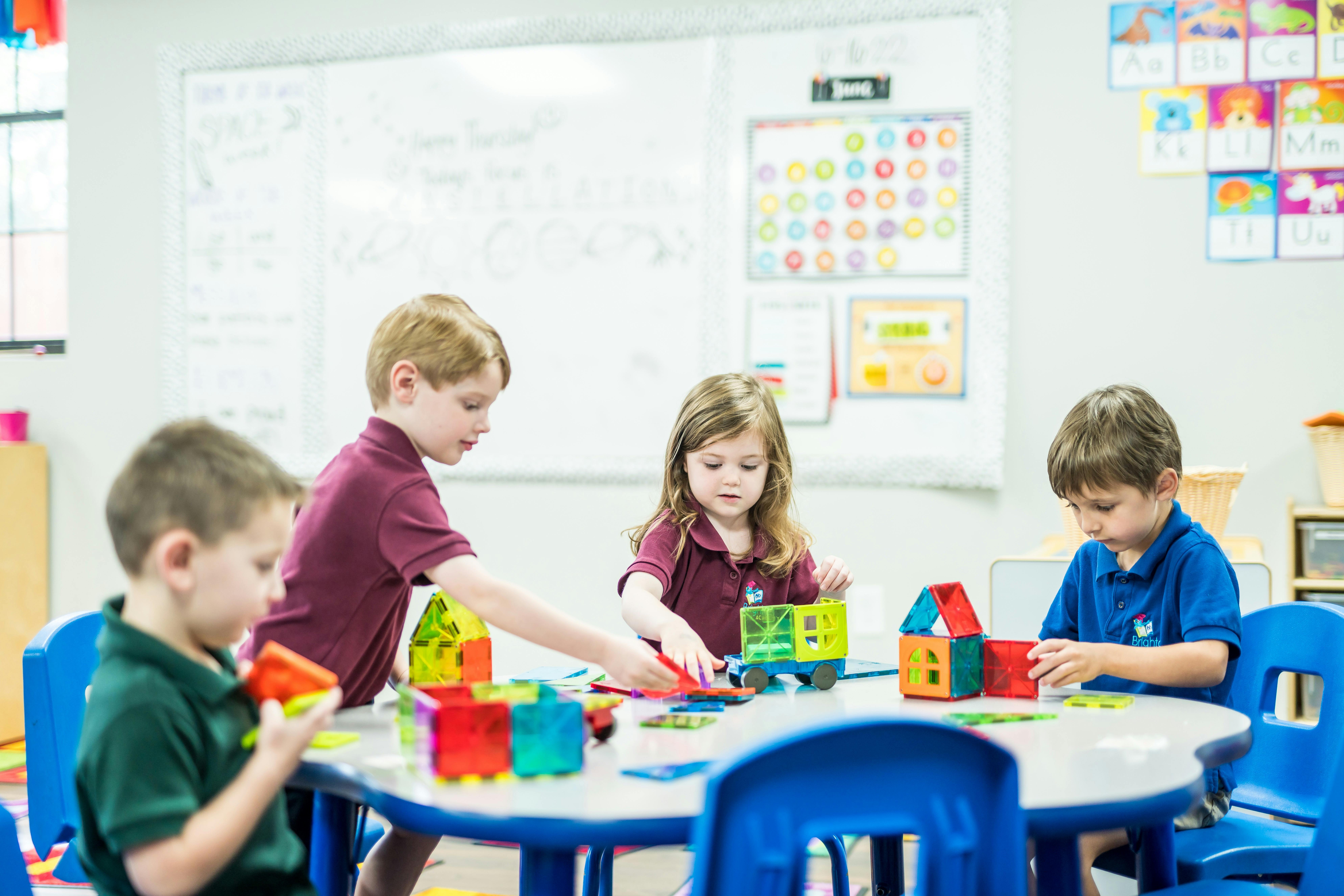 Children playing with colorful building blocks at a table in a classroom