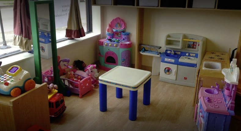 Playroom with toy kitchen, table, and other toys