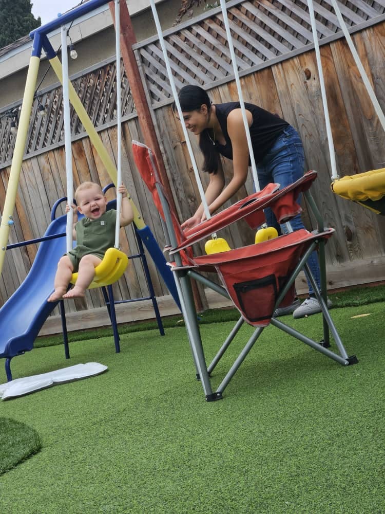 Person standing near a child on a swing set