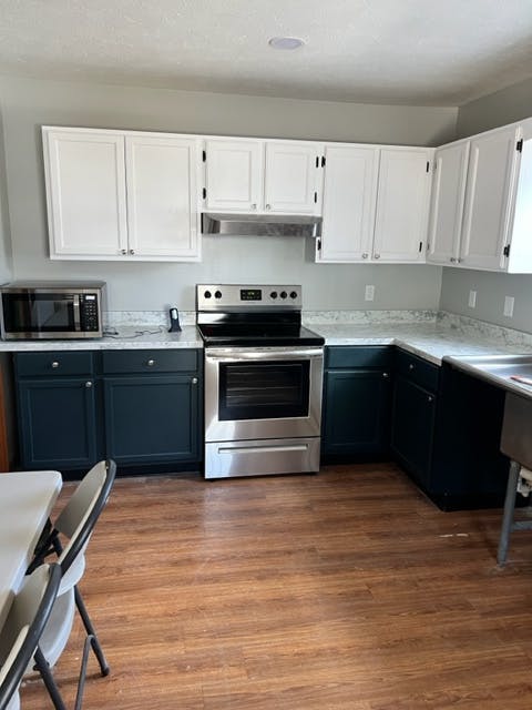Kitchen with white upper cabinets, dark lower cabinets, and stainless steel appliances