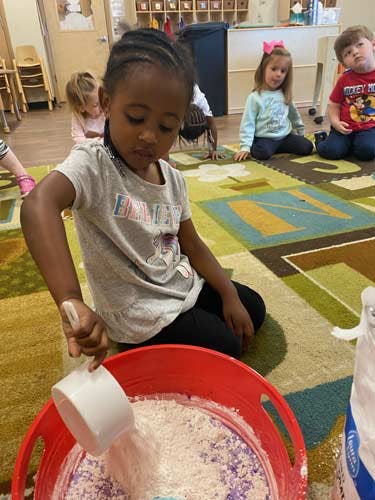 Child scooping white powder from a red bin