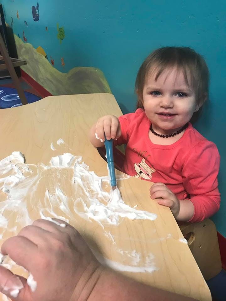 Child playing with shaving cream on a table