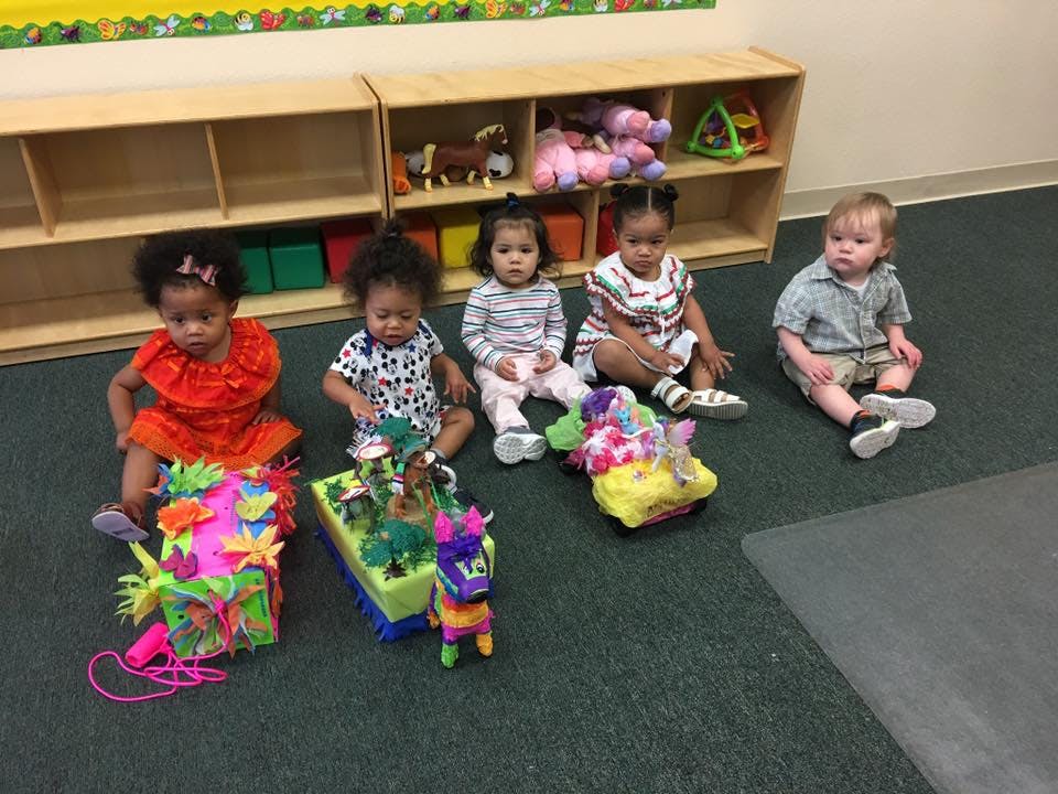 Five children sitting on the floor with toys