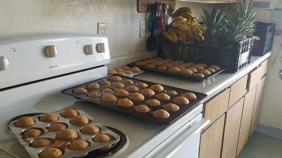 Trays of baked muffins on a kitchen counter next to a stove