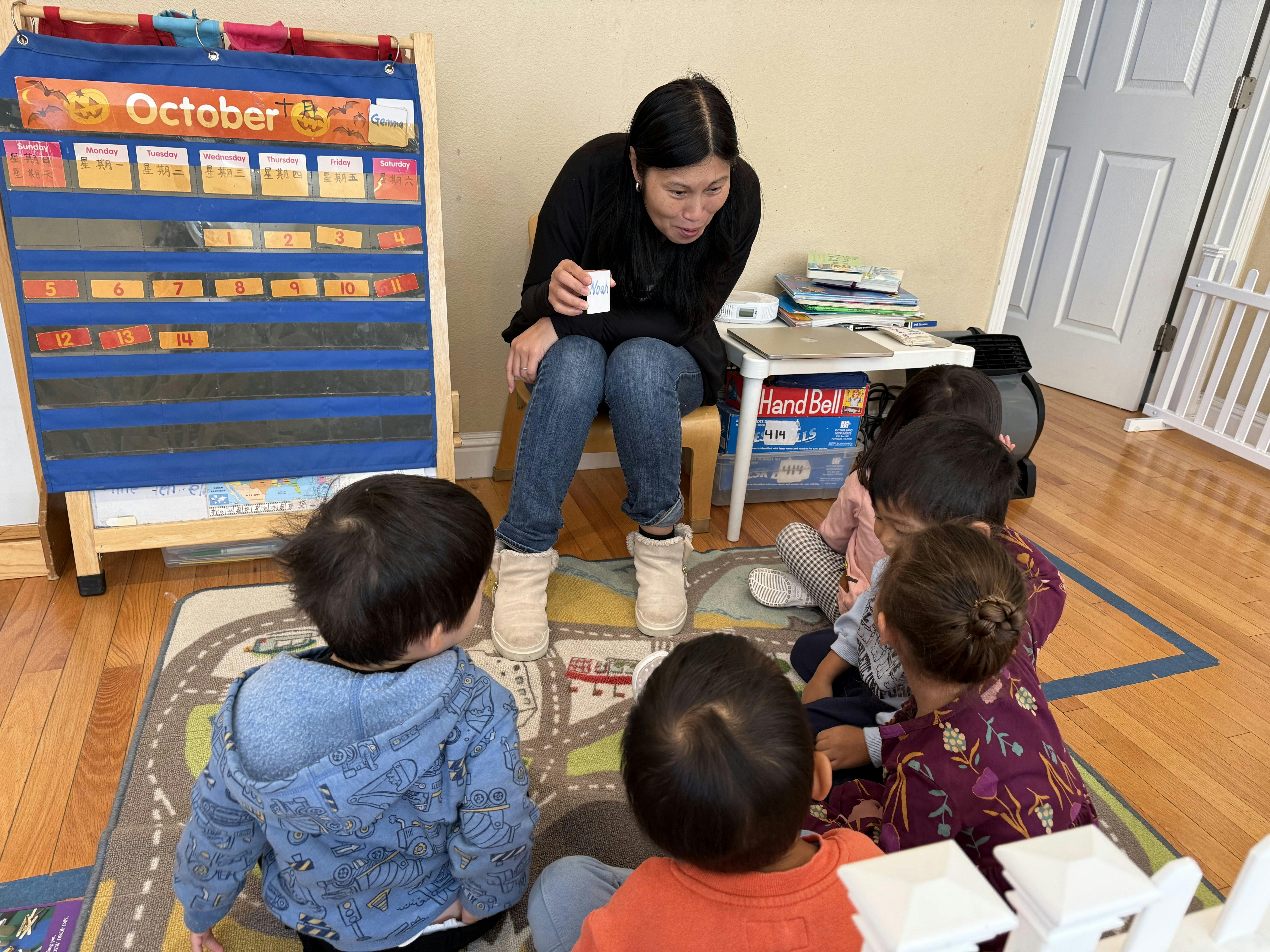 Person sitting on a chair with children sitting on a rug in a classroom