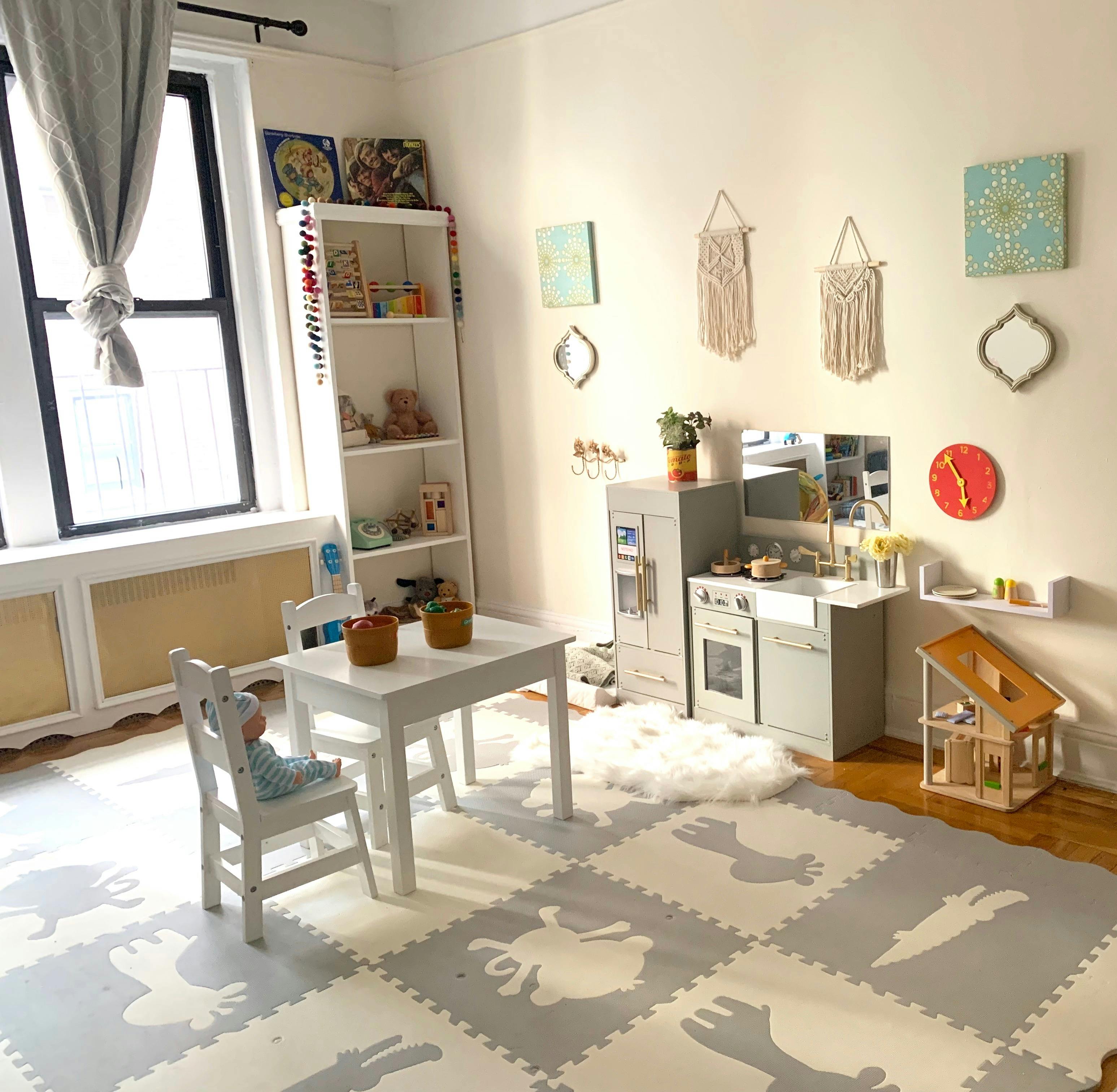 Child's play area with a small table and chairs, play kitchen, and bookshelf