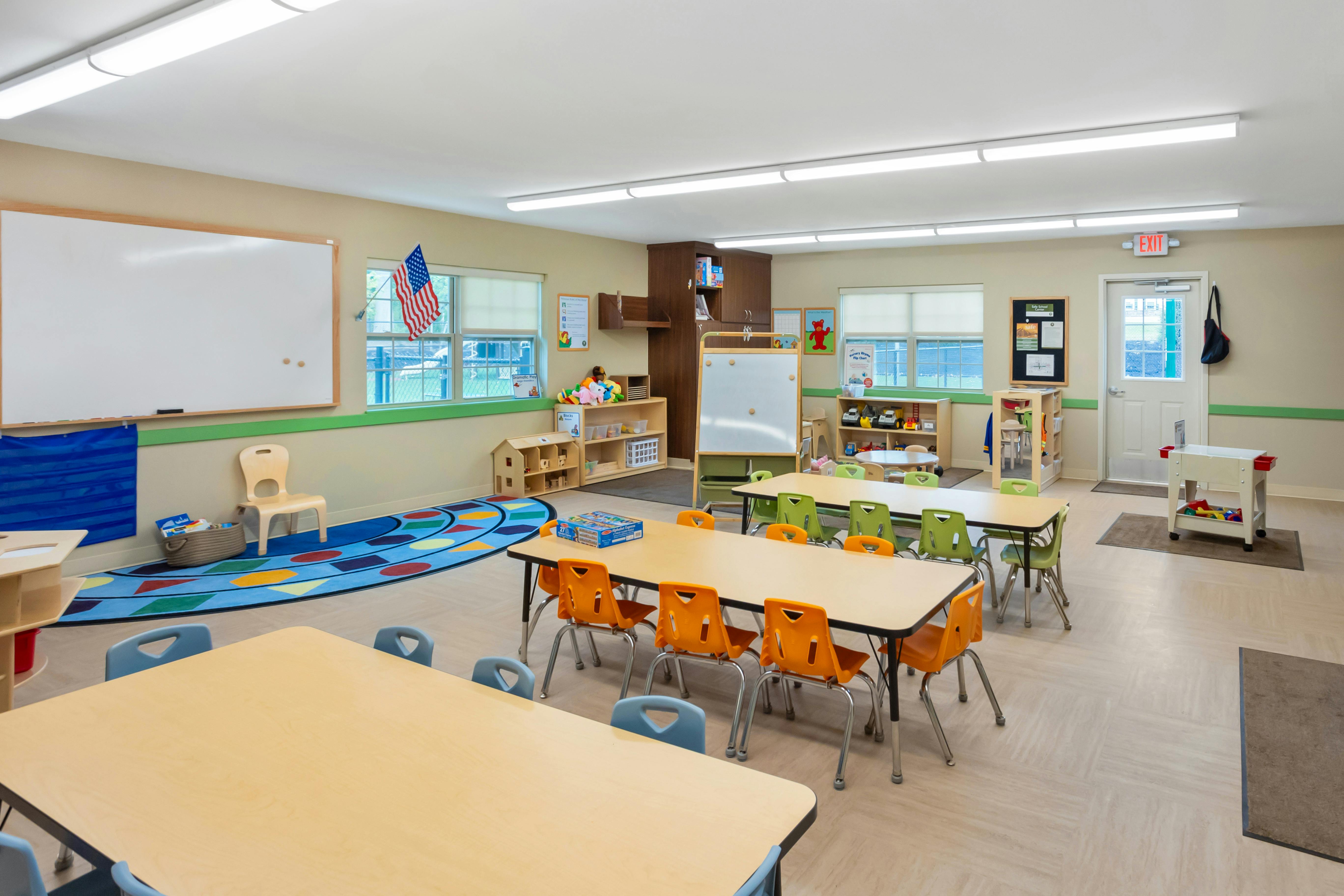 Classroom with multiple tables and chairs, toys, and a whiteboard