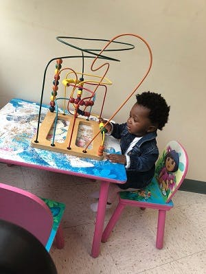 Child playing with a bead maze toy on a table