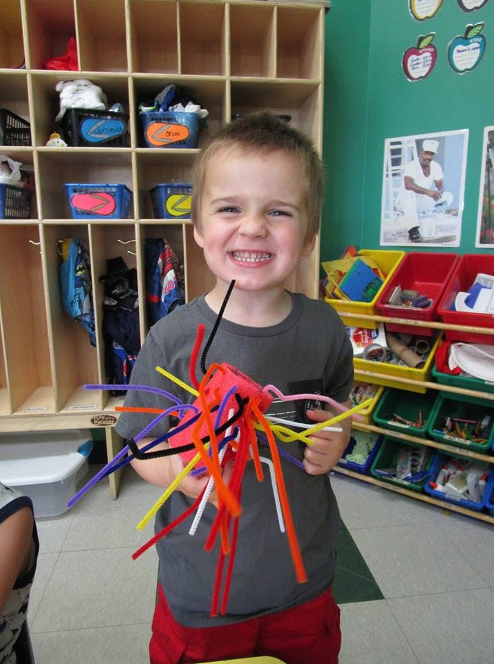 Child holding a craft made of pipe cleaners