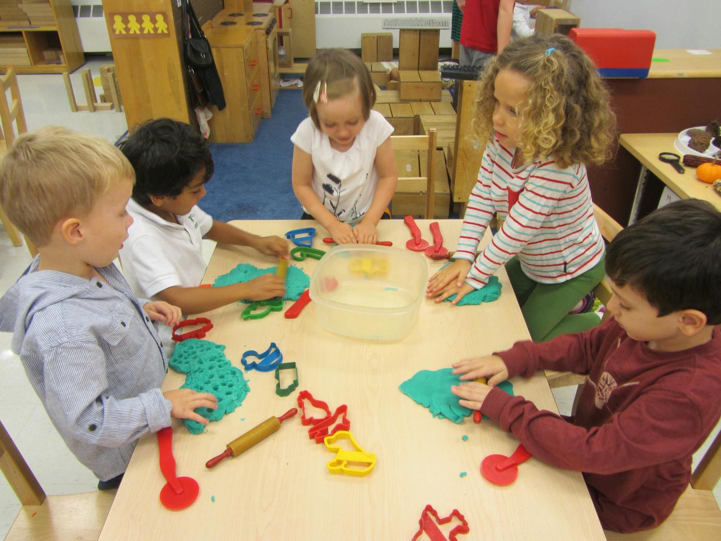 Children playing with modeling clay and cookie cutters at a table