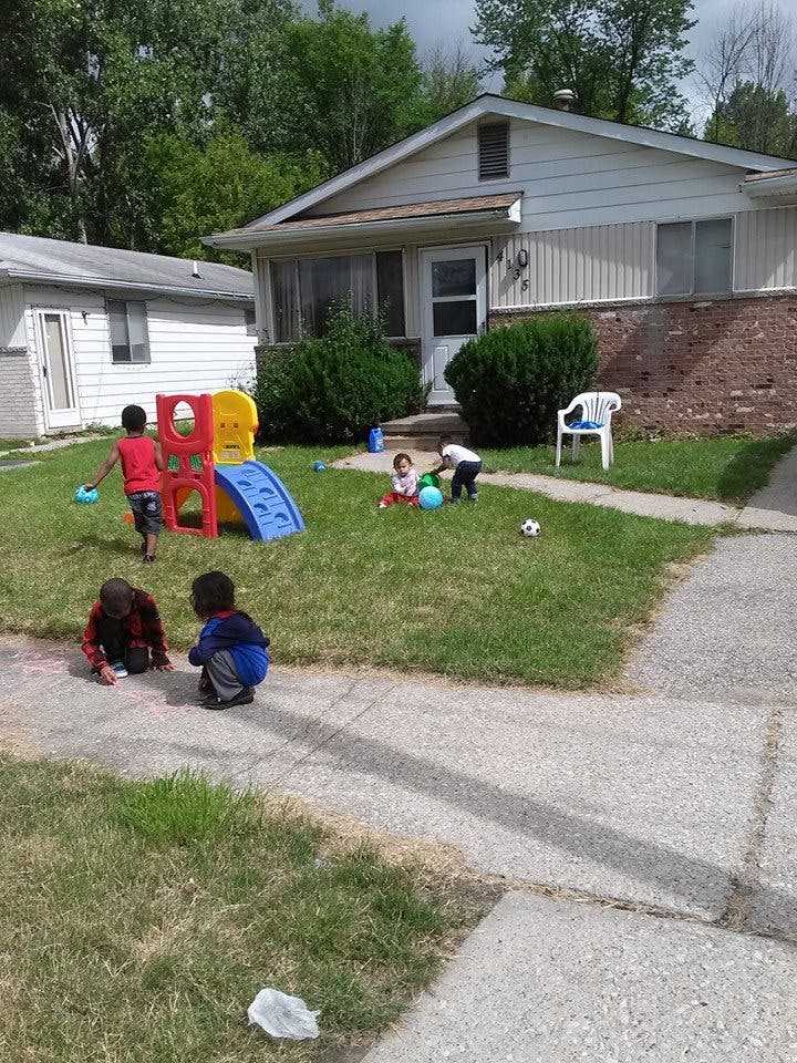 Children playing in a yard with a slide and drawing on a sidewalk