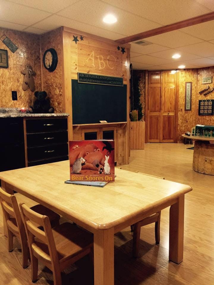 Children's table and chairs with a book on top in a room with a chalkboard