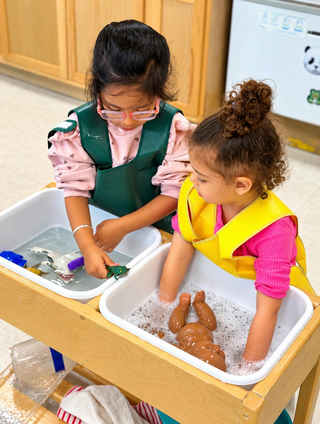 Two children playing with toys in water basins