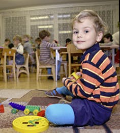 Child sitting on floor with toys in a classroom