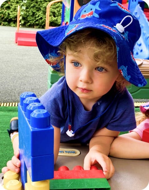 Child in a shark hat playing with large building blocks