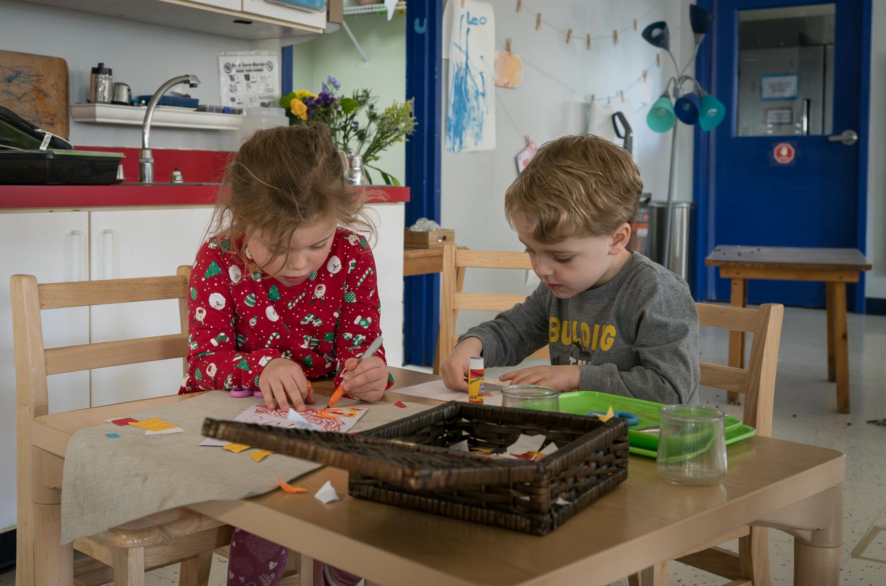 Two children sitting at a table doing crafts