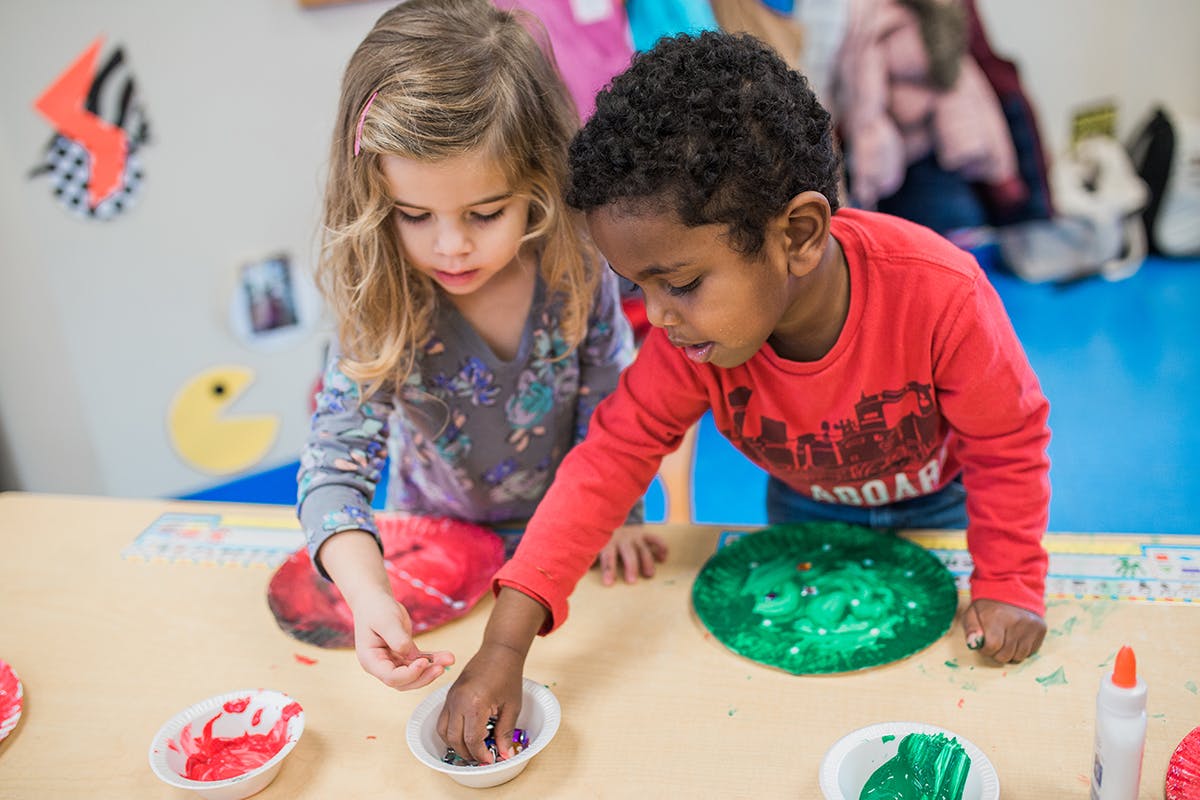 Two children playing with slime at a table