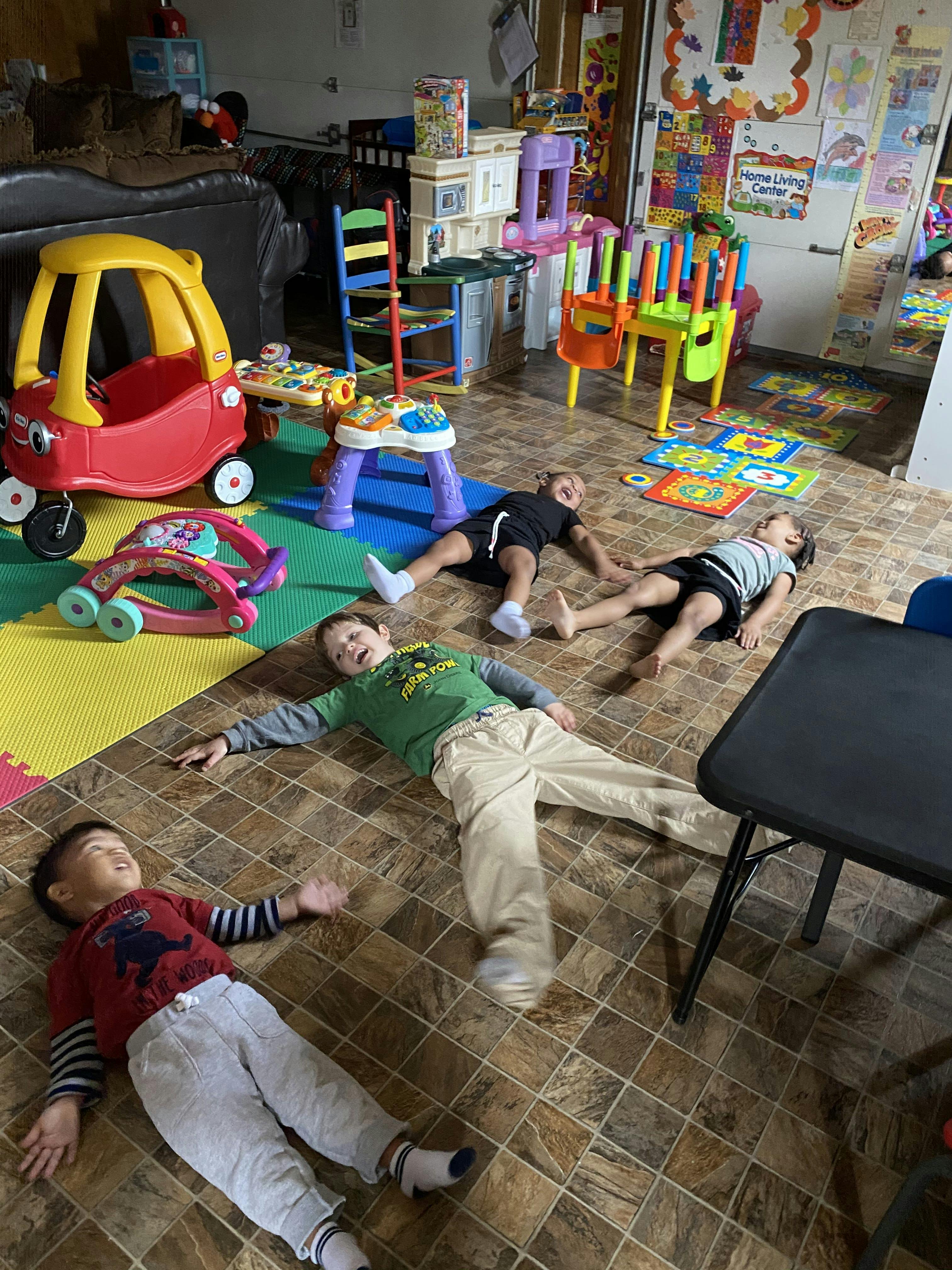 Four children lying on the floor in a playroom