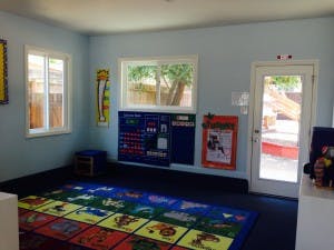 Empty classroom with colorful rug and windows