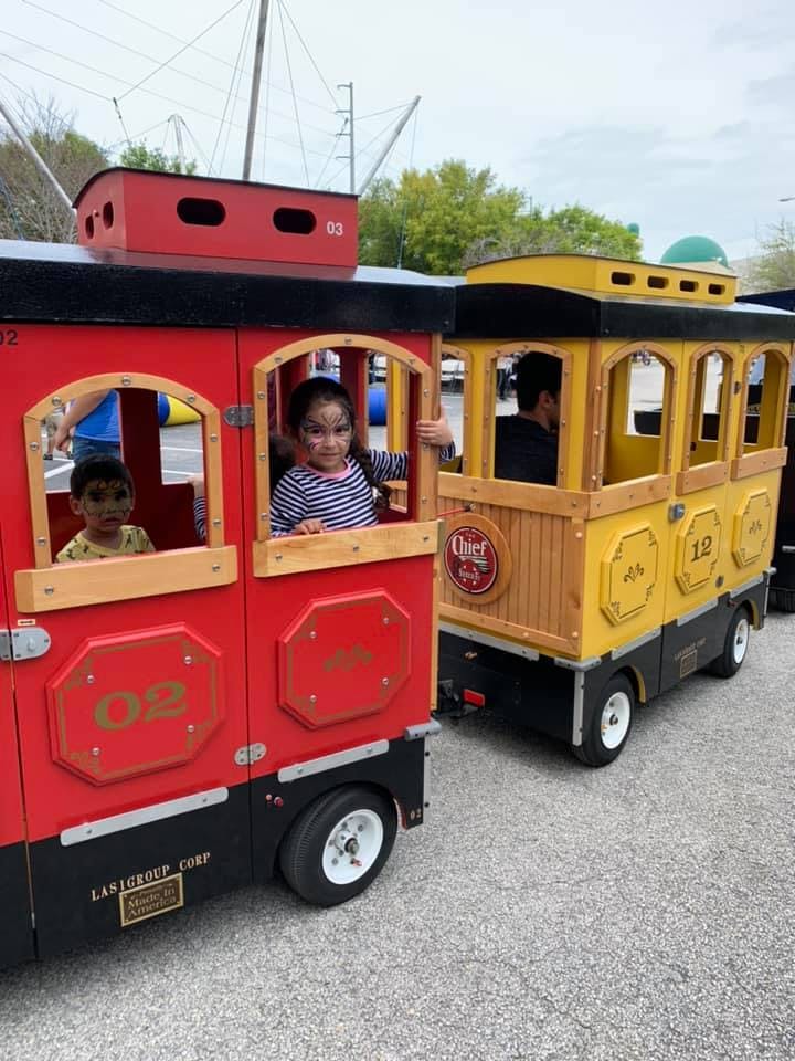 Two children riding in a red and yellow miniature train