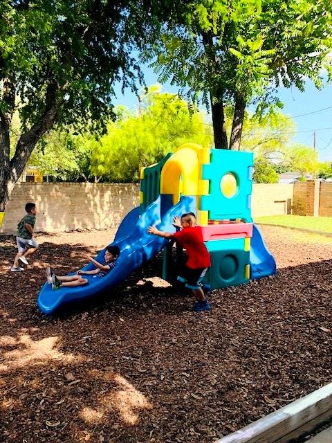 Three children playing on a colorful playground slide