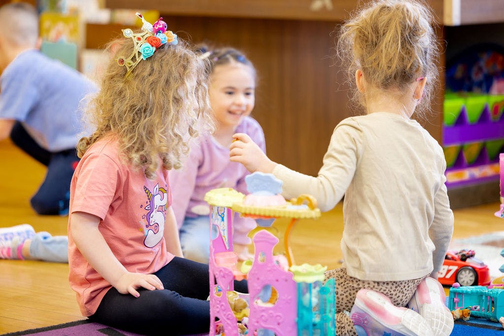 Three children playing with toys on the floor