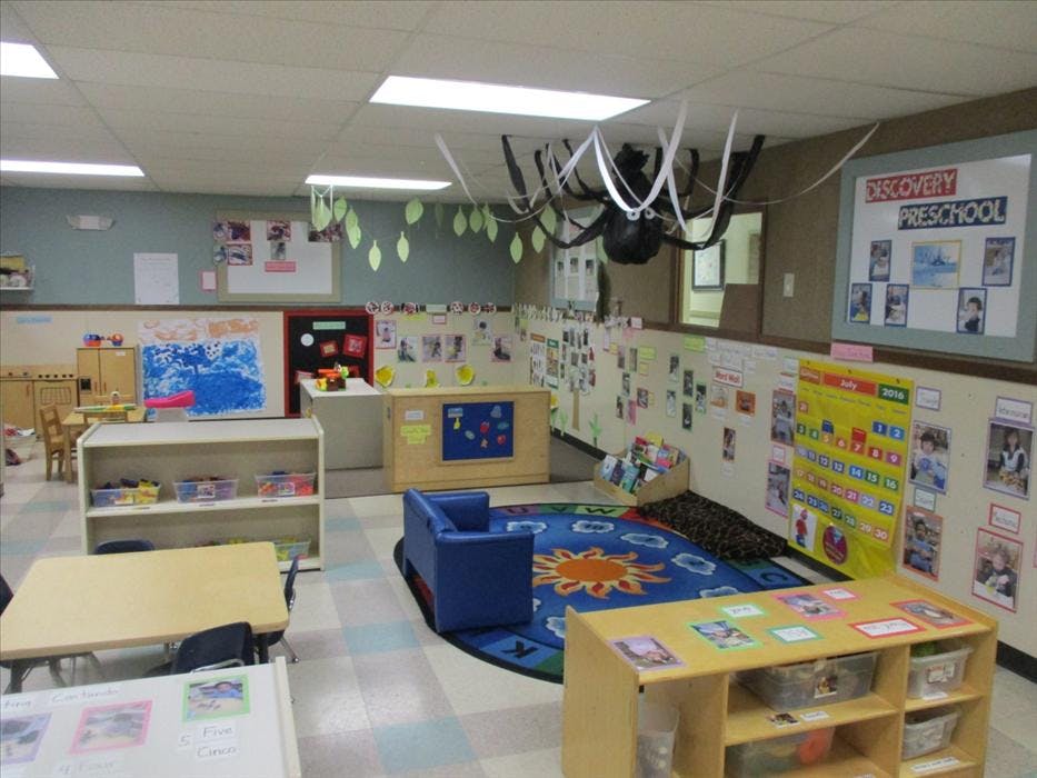 An empty preschool classroom with colorful decorations, small tables, and play areas