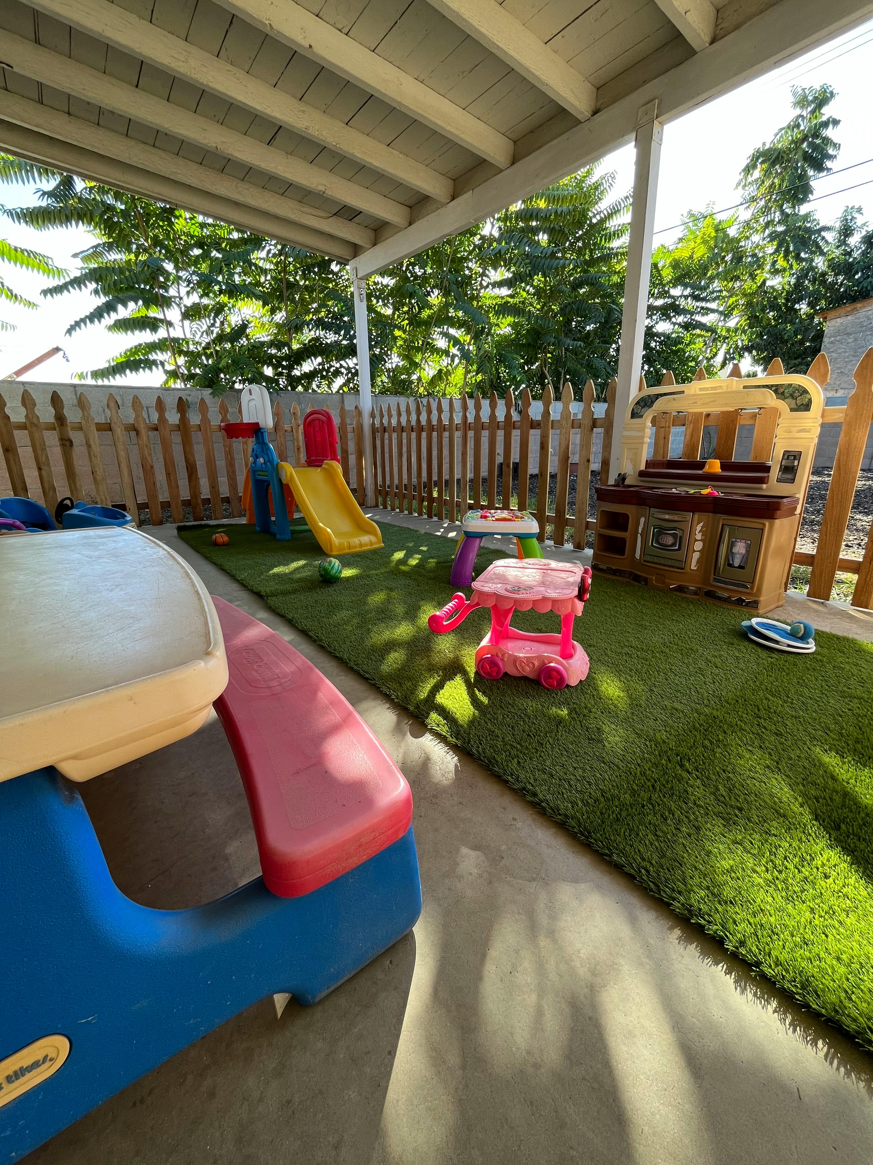 Outdoor play area with artificial turf, slide, and play kitchen