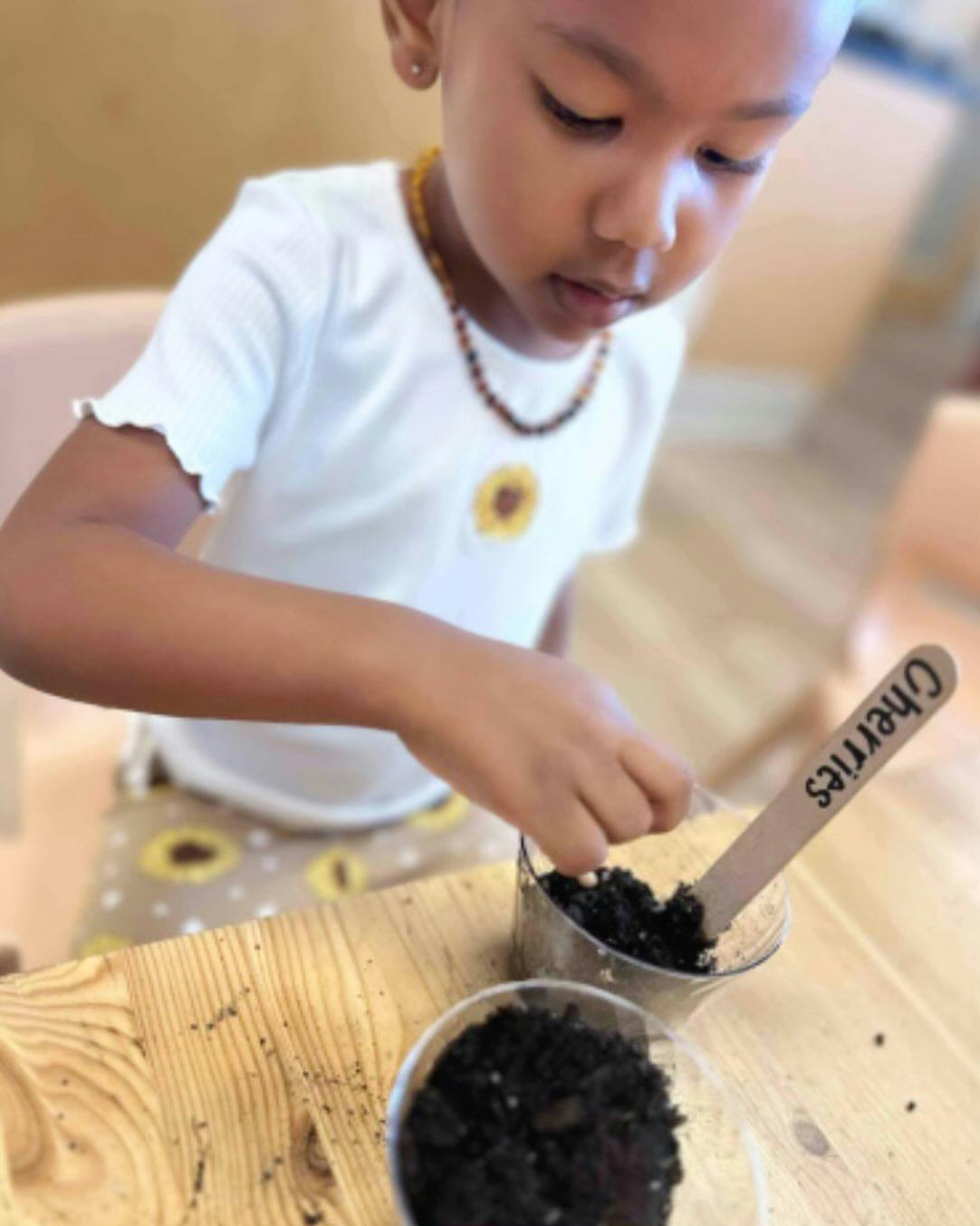 Child planting in small pots with soil