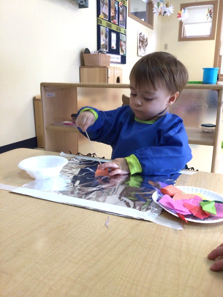 Child in a blue smock painting on foil atable