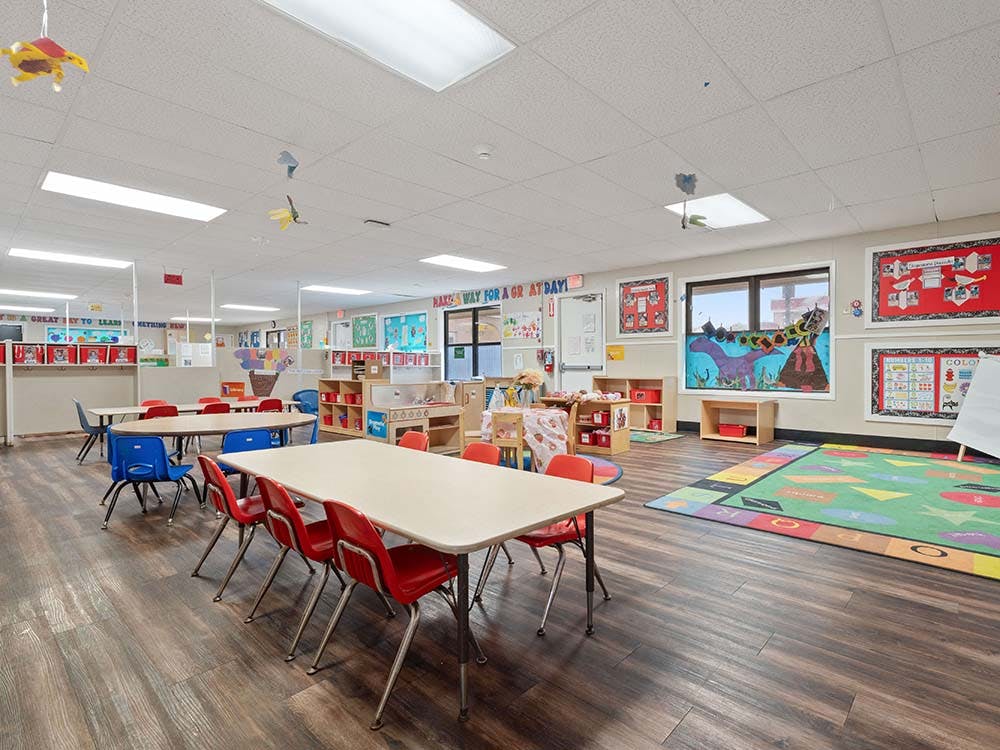 Empty classroom with small tables, colorful chairs, and educational decorations