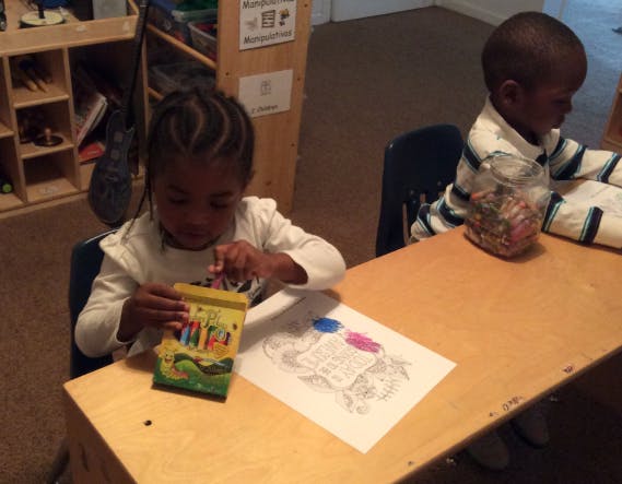 Child coloring at a table with another child