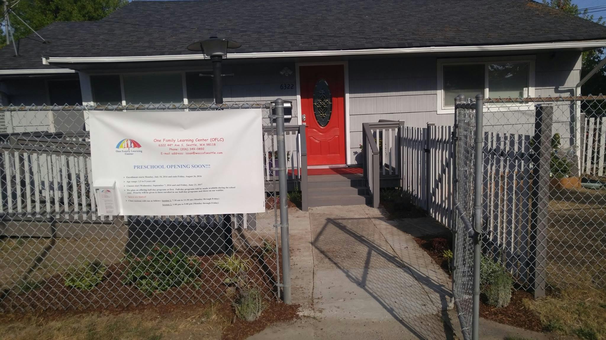 House with red door behind a chain link fence with a banner