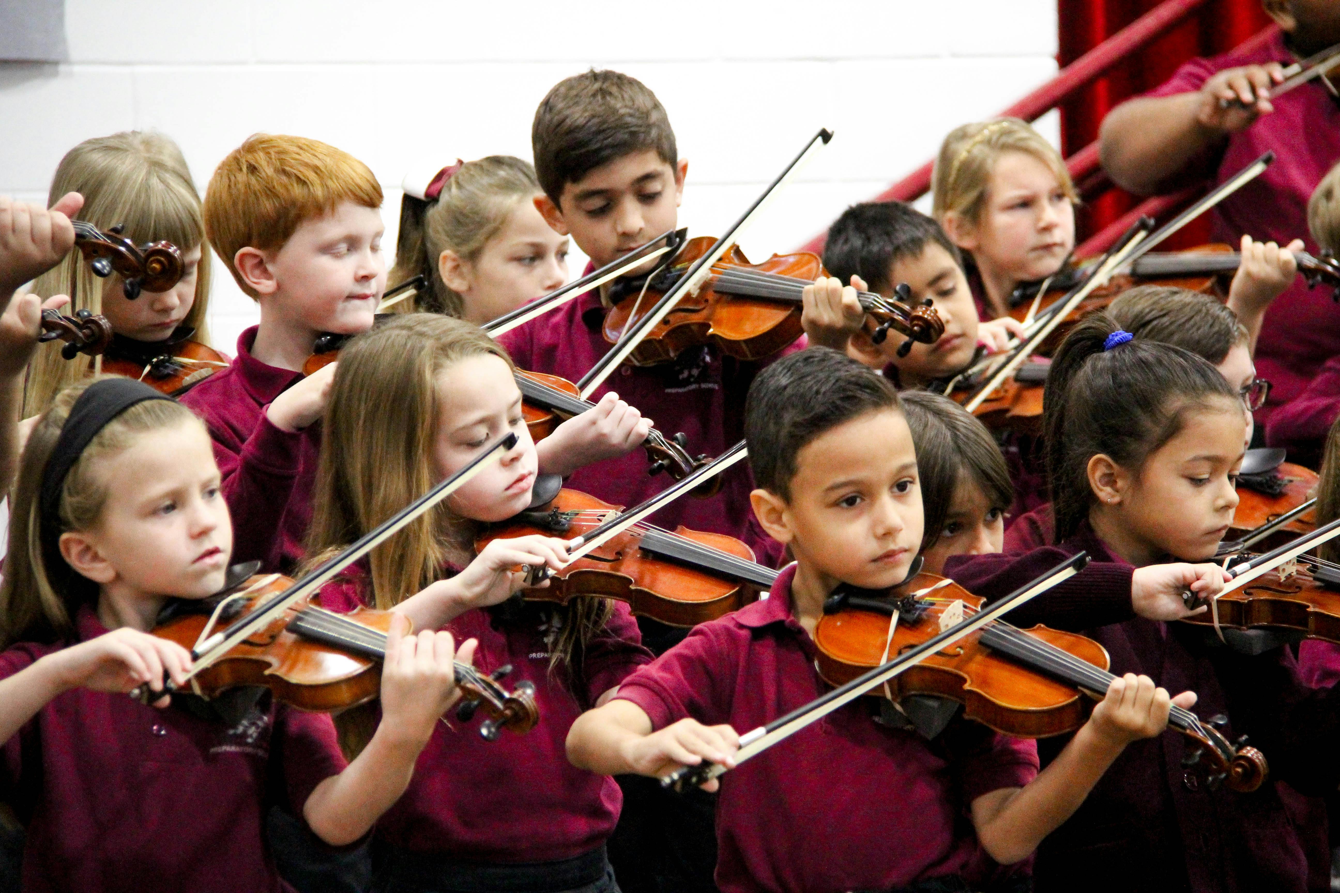 Children playing violins in an orchestra