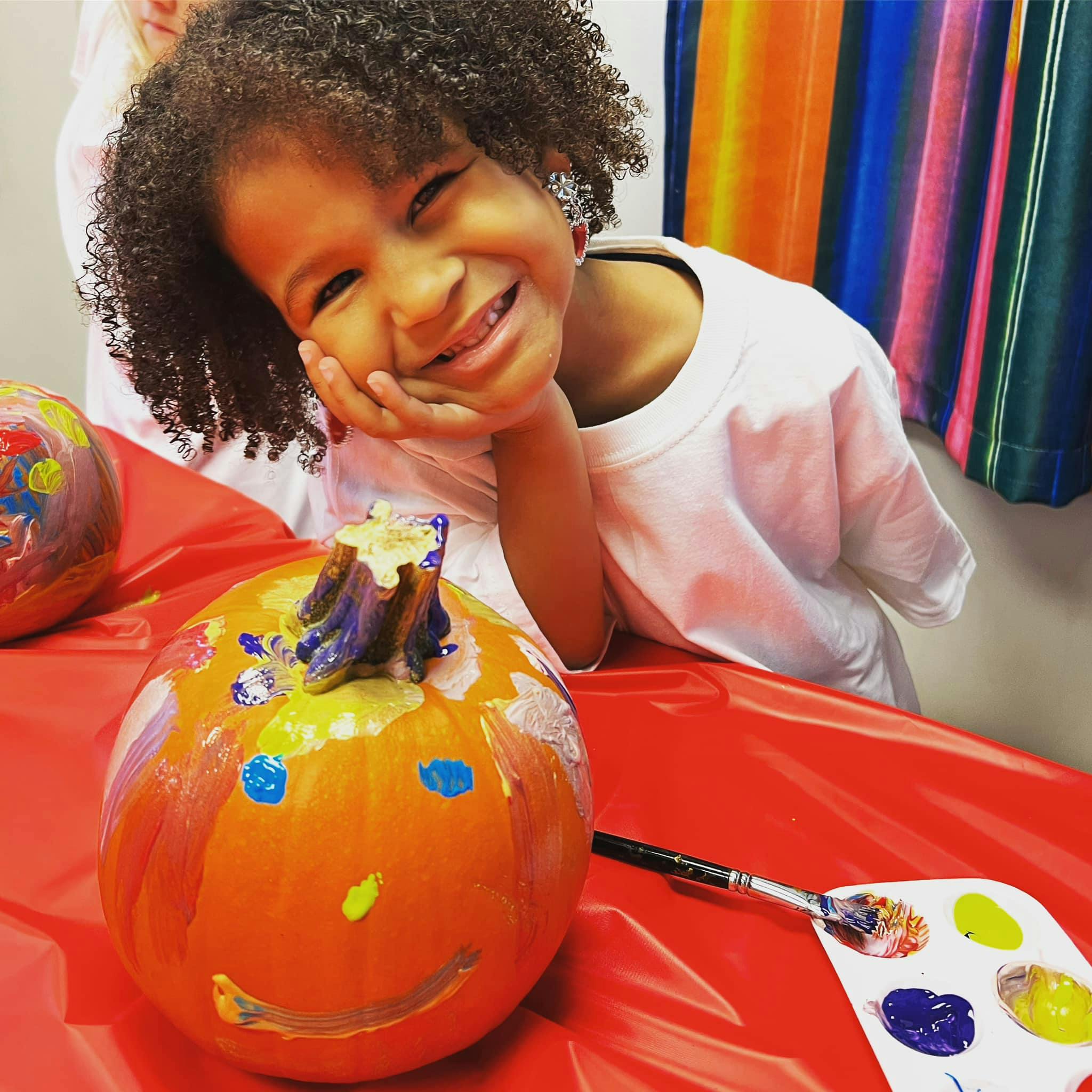 Child with painted pumpkin and paint palette