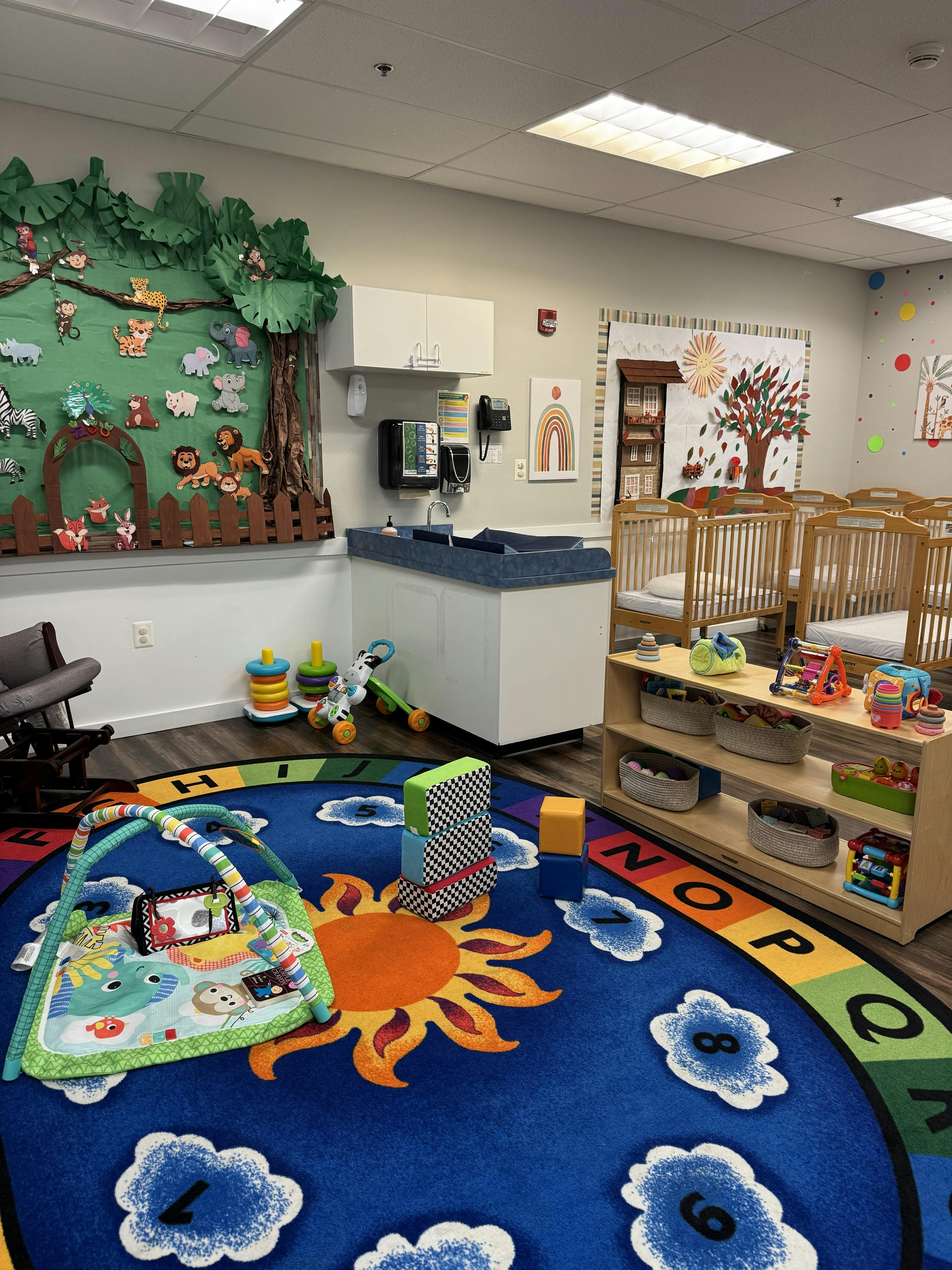 A colorful childcare classroom with cribs and an alphabet play mat