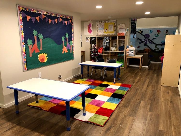 Classroom with tables, colorful rug, and bulletin board