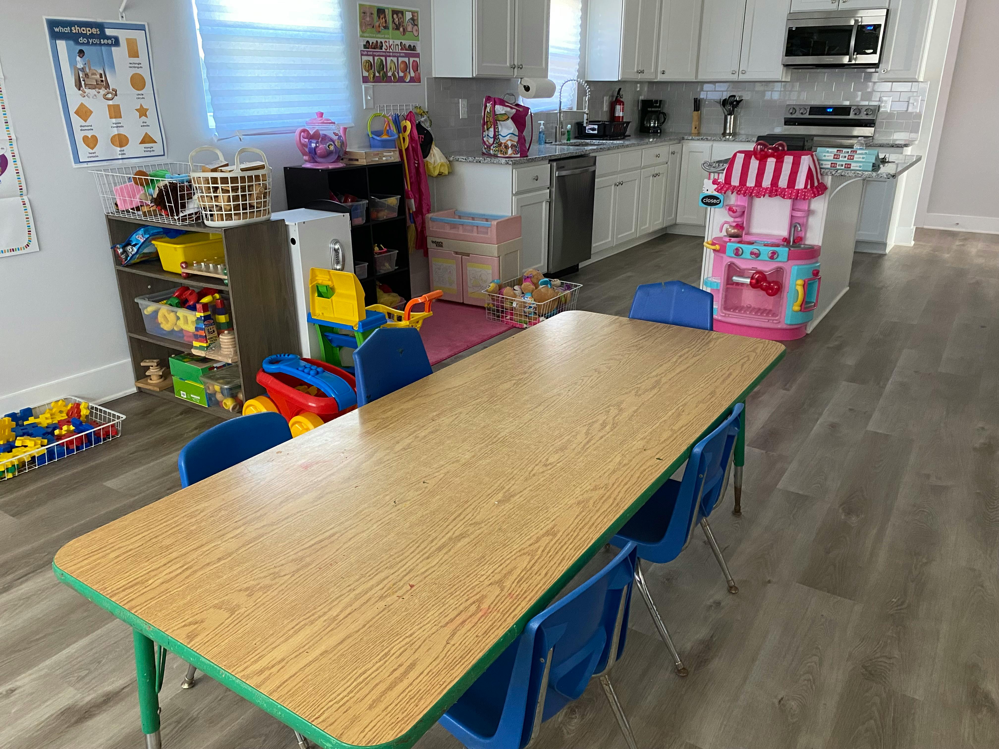 Children's play area with a long table and chairs in front of a kitchen