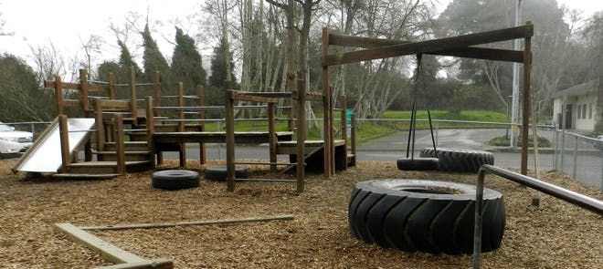 Playground with wooden structures, slide, tire swings, and large tires