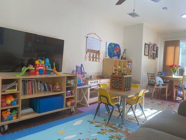 Playroom with a television, toy shelf, small table and chairs, and play kitchen